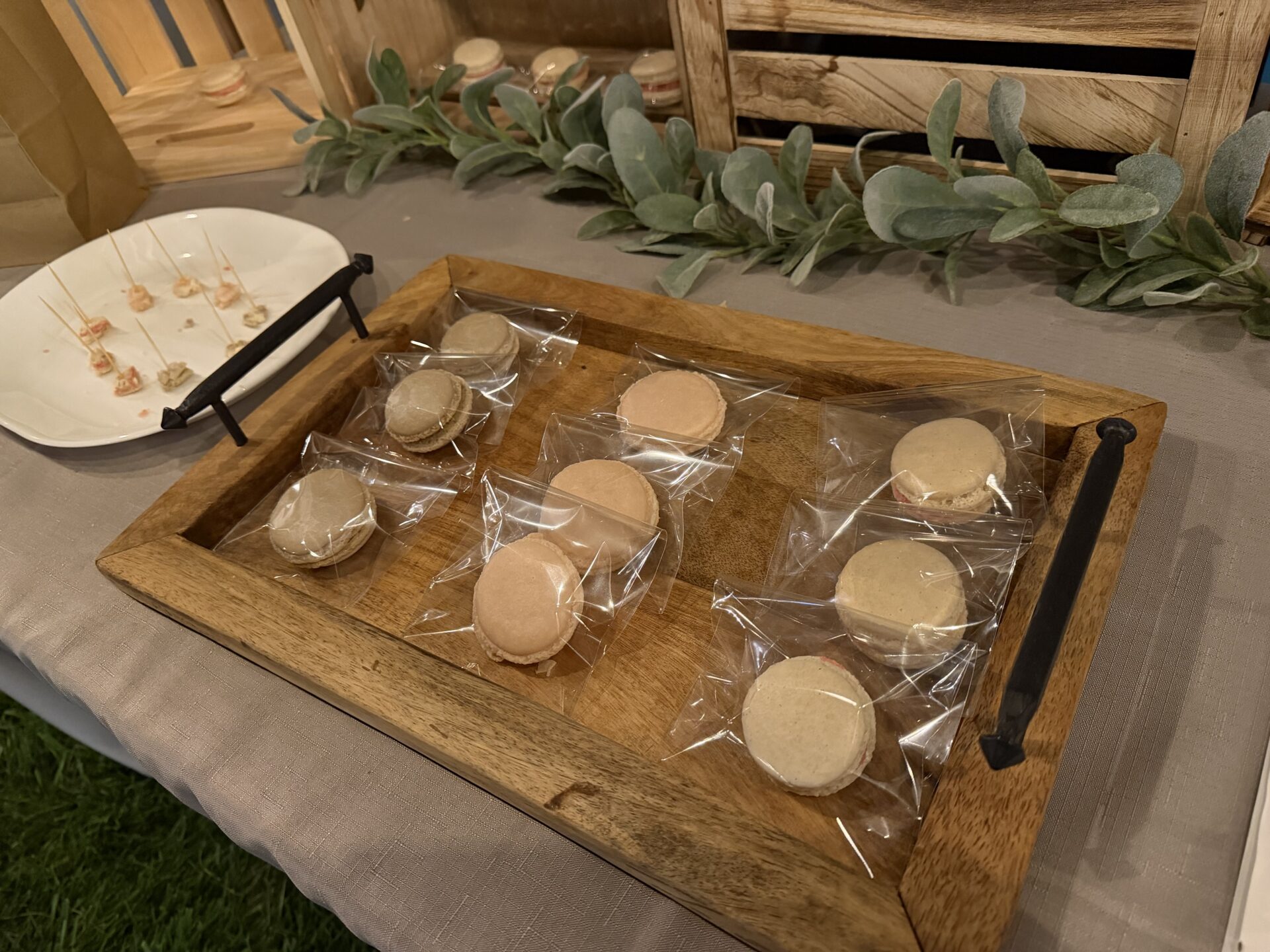 Individually packaged handmade macarons arranged on a wooden serving tray